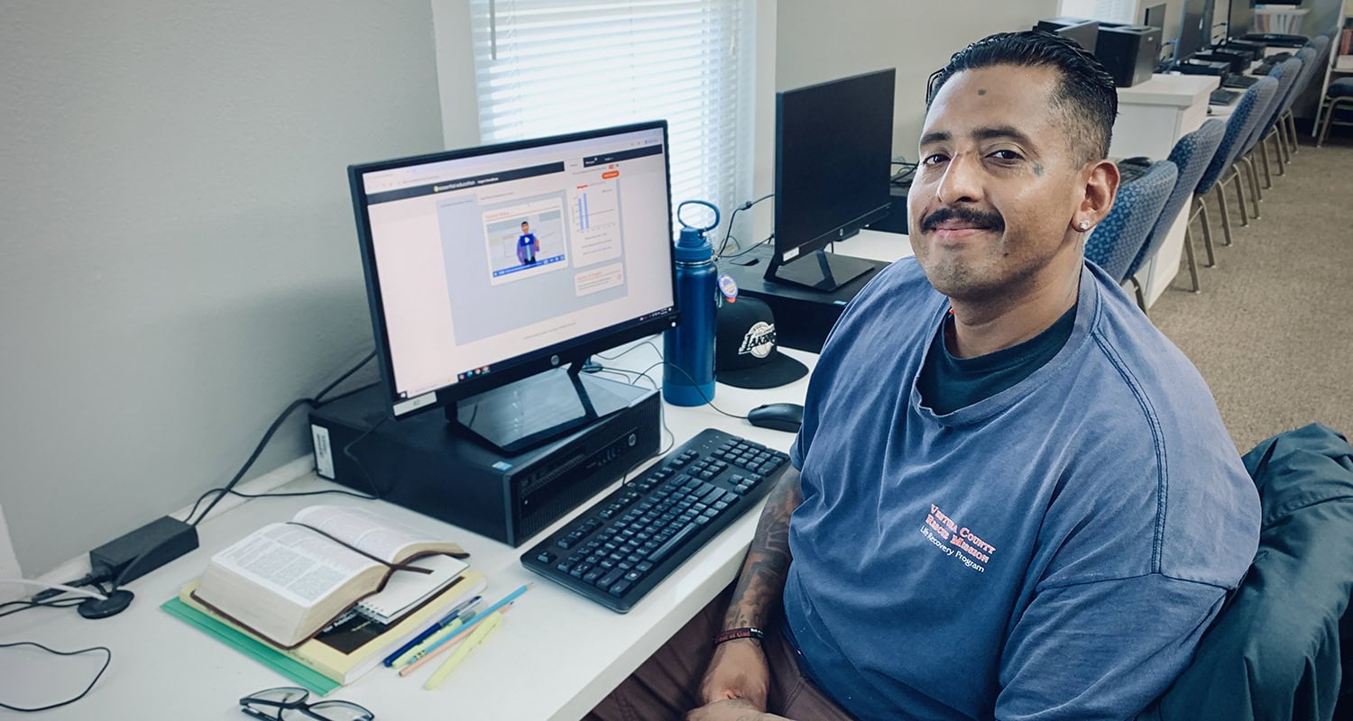 Volunteer working at a computer in Rescue Mission Alliance Ventura County office, helping those in need.