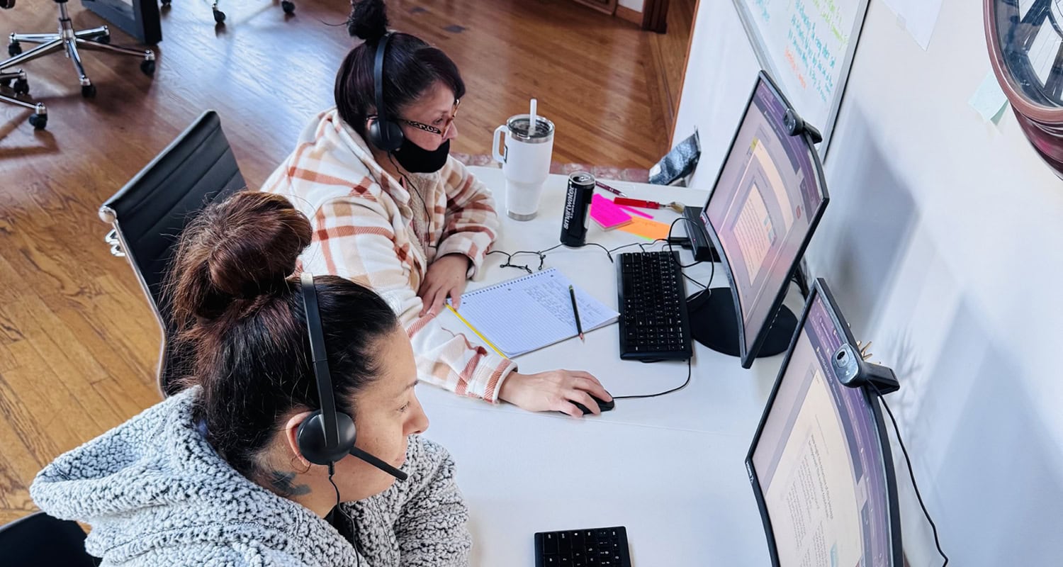 Providing assistance to a woman with headphones in a call center or office environment.