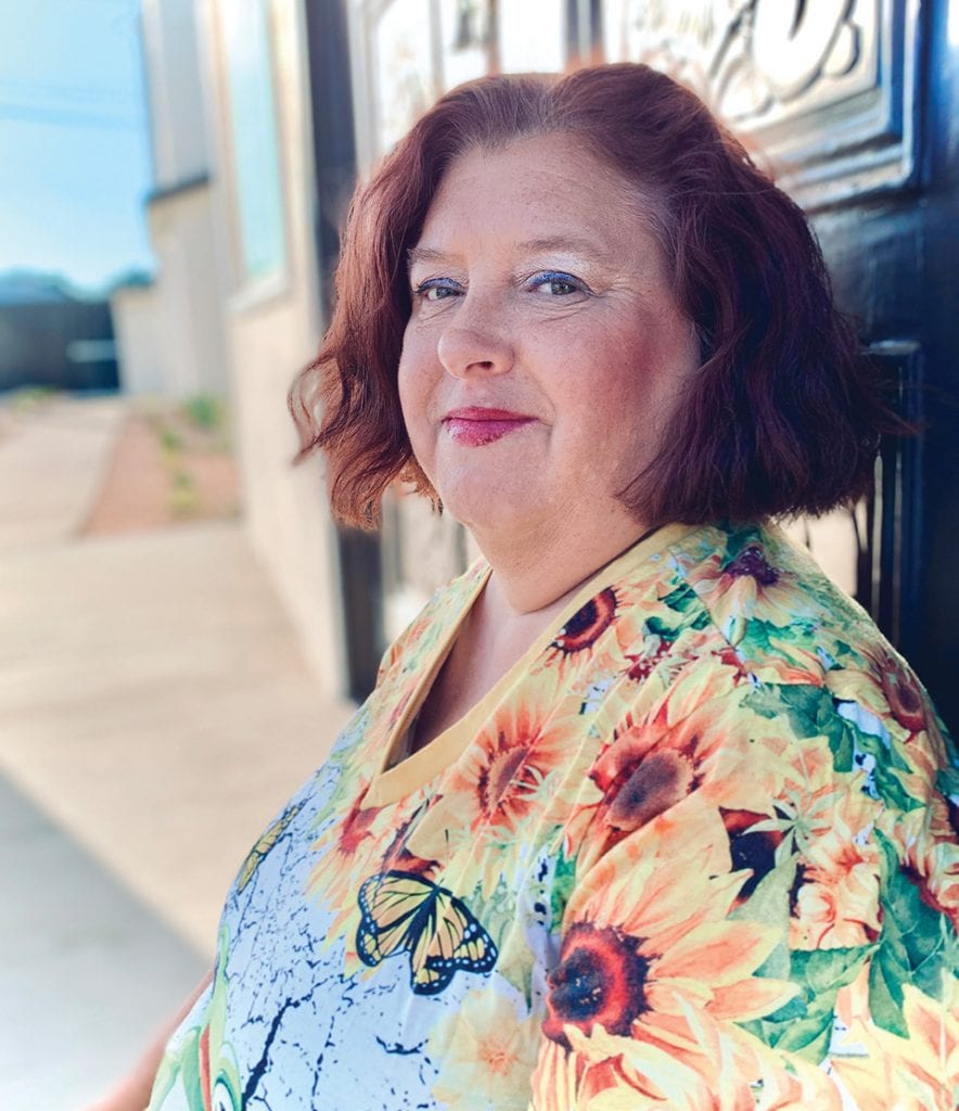 Woman with red hair wearing floral blouse standing outside near Rescue Mission Ventura County.