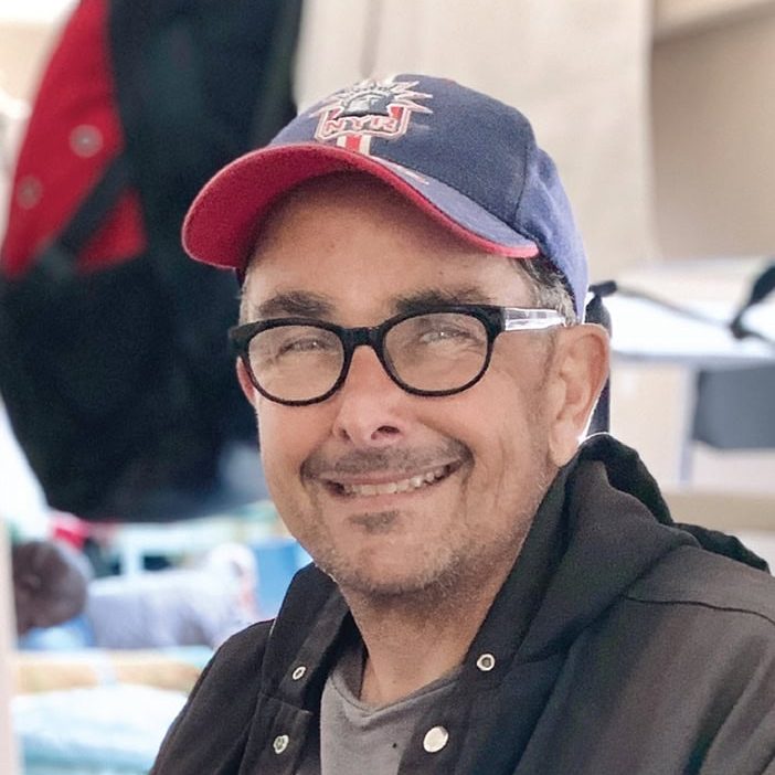 Man smiling wearing glasses and a baseball cap at Rescue Mission Ventura County.