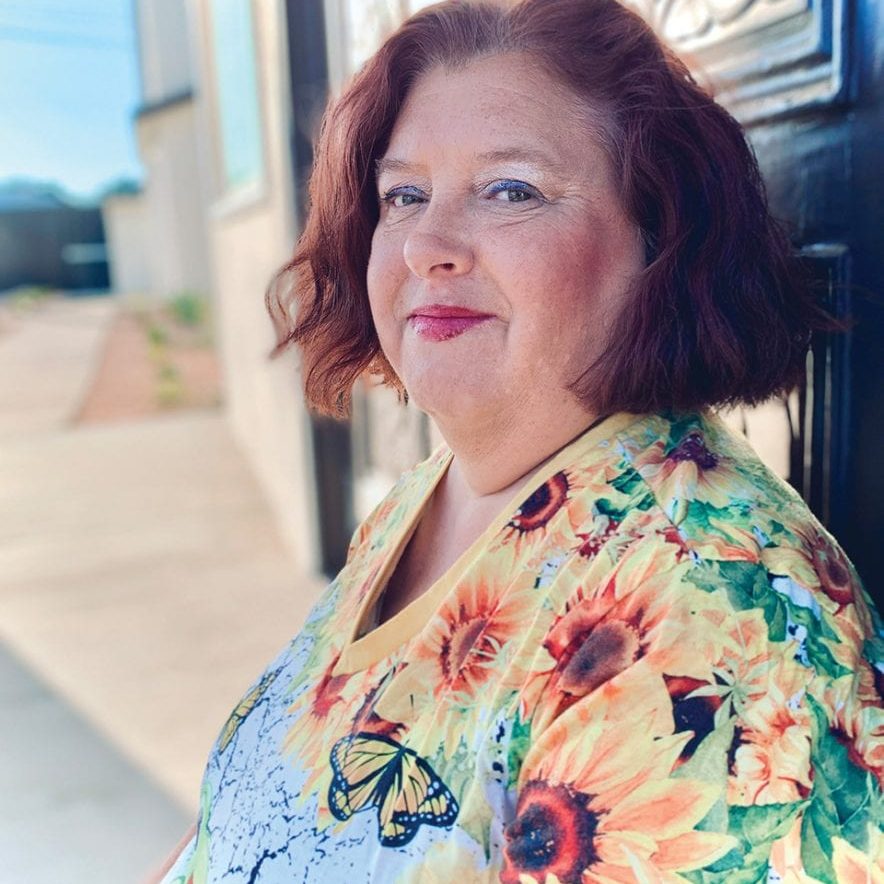 Woman with red hair wearing floral blouse standing outside near Rescue Mission Ventura County.