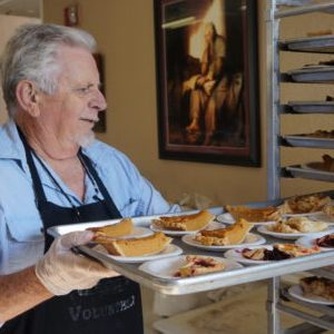 Man moving a sheet pan filled with pumkin pie to a rack